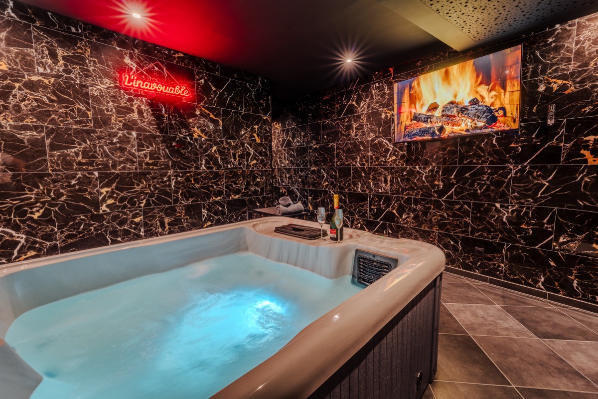 Privéspa met bruisende jacuzzi, zwarte marmeren muur en neonbord — love room L'Inavouable in Marquise