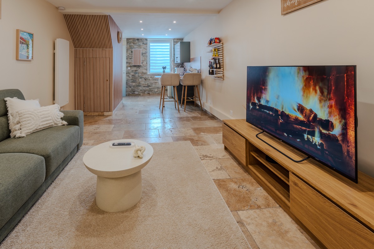 Lichte woonkamer met bank en smart-tv, open naar de keuken — L'Inavouable, Côte d'Opale